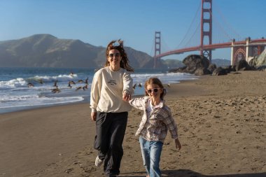 Anne ve kızı sahilde eğleniyor, kadınlara odaklanıyor.