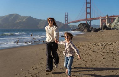 Anne ve kızı sahilde eğleniyor, kadınlara odaklanıyor.