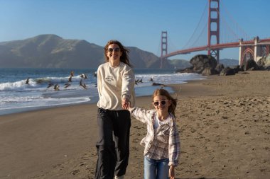 Anne ve kızı sahilde eğleniyor, kadınlara odaklanıyor.