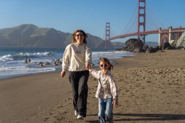 Anne ve kızı sahilde eğleniyor, kadınlara odaklanıyor.