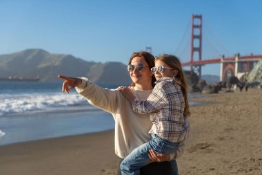Anne ve kızı sahilde eğleniyor, kadınlara odaklanıyor.