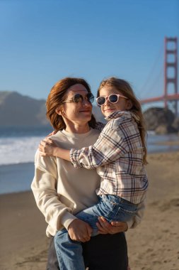 Anne ve kızı sahilde eğleniyor, kadınlara odaklanıyor.