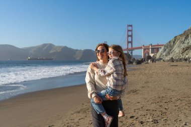 Anne ve kızı sahilde eğleniyor, kadınlara odaklanıyor.