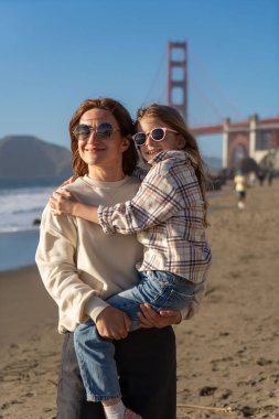 Anne ve kızı sahilde eğleniyor, kadınlara odaklanıyor.