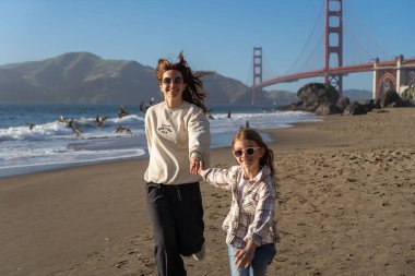 Anne ve kızı sahilde eğleniyor, kadınlara odaklanıyor.