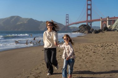 Anne ve kızı sahilde eğleniyor, kadınlara odaklanıyor.