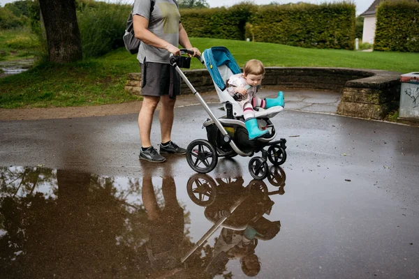 Baba Kızıyla Parkta Yürüyor Bebek Arabasıyla Yağmurdan Sonra Birikintisine Bakıyor — Stok fotoğraf