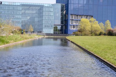 Yeni modern cam binalar, güzel çimenleri ve su dolu bir kanalı var.