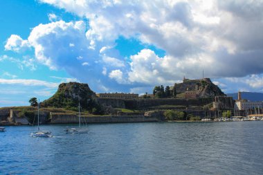 Güneş tarafından aydınlatılan ve kara bulutlarla kaplanmış güzel tarihi Korfu kasabasının manzarası.