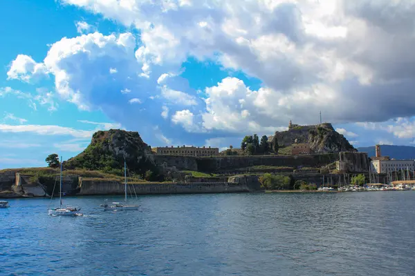 Güneş tarafından aydınlatılan ve kara bulutlarla kaplanmış güzel tarihi Korfu kasabasının manzarası.