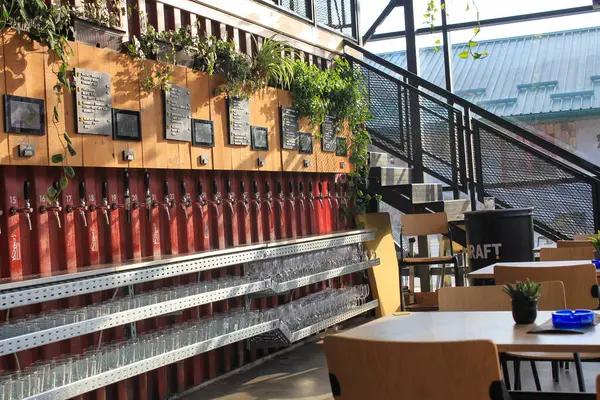 Küçük masaları ve bağımsız muslukları olan büyük bir bira salonu.