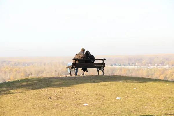 Bir adam ve bir kız New Belgrad manzaralı bir tepede oturuyorlar.