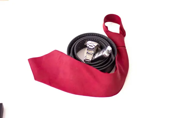 siyah deri kemer, saat, araba anahtarı ve kırmızı kravat.