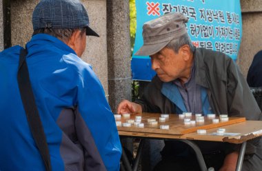 Güney Kore, Seul 'de kaldırımda mahjong oynayan yaşlı bir adam..