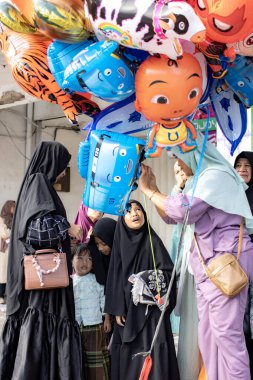 Jakarta, Endonezya - 31 Mart 2025: Matraman Raya yol kesişimindeki Kurban namazı sonrası balon satıcısı, Jatinegara, Jakarta.