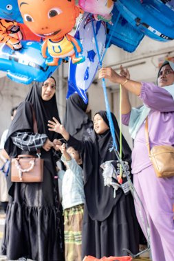 Jakarta, Endonezya - 31 Mart 2025: Matraman Raya yol kesişimindeki Kurban namazı sonrası balon satıcısı, Jatinegara, Jakarta.