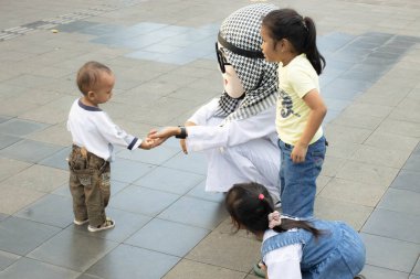 Jakarta, Endonezya - 15 Nisan 2025: Arap kostümlü bir adam oyuncak bebek kafası takıyor ve çocuklarla şakalaşıyor.