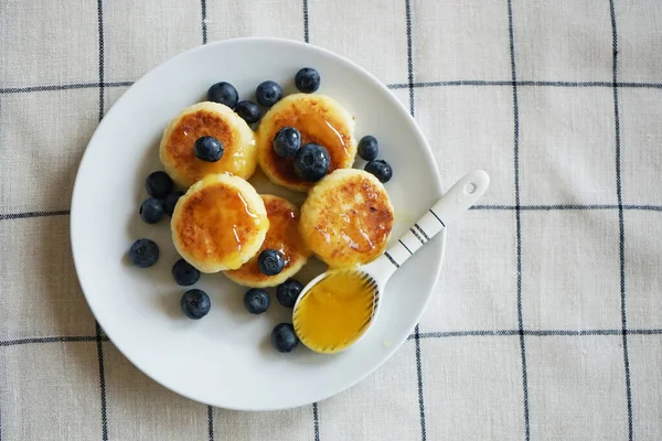 stock image Homemade cheese dessert with honey and blueberries on a checkered linen tablecloth                               