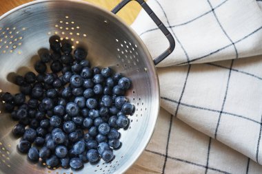 Kareli masa örtüsü üzerinde metal kevgir böğürtlen.