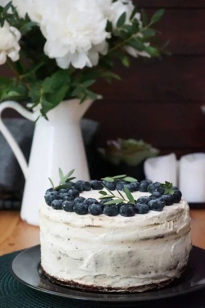 背の高いケーキクリームチーズと背景に牡丹の白い花瓶とブルーベリーを飾る — ストック写真