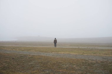  Yalnız bir adam beyaz sisle kaplı bir tarlada duruyor.