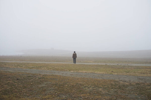  Одинокий человек стоит в поле, покрытом белым туманом