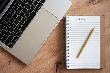 Kalemle birlikte not defteri ahşap bir masada dizüstü bilgisayarın yanında duruyordu.