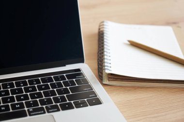Kalemle birlikte not defteri ahşap bir masada dizüstü bilgisayarın yanında duruyordu.