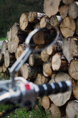 Klasik siyah bir motosikletin sapı ağaç kesimlerinin arka planına karşı.