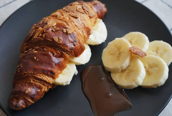 Croissant Francês Com Amêndoas Banana Molho Chocolate Uma Placa Preta — Fotografia de Stock