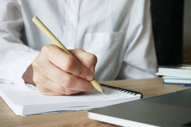 Beyaz tişörtlü bir kız dizüstü bilgisayarın yanına elini koyuyor.