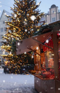 Noel ağacının ve düşen karın arka planında sıcak şarap ve her türlü yiyecekle dolu bir dükkan.