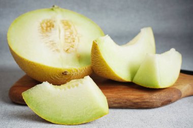 Gri arka planda tahta bir tahtada dilimlenmiş sulu kavun.