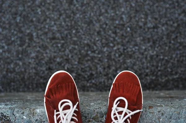 用鹅卵石衬托在石墩上的绒毛红运动鞋 — 图库照片