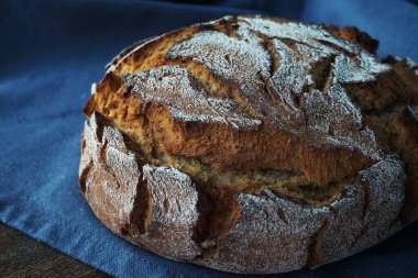 Tahtada taze ekmek ve gri bir masa örtüsü var.