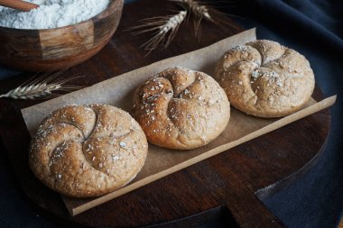 Arkaplanda taze ekmek, üzerinde un ve koyu arkaplanda tahta bir tahta var.