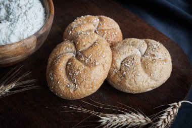 Arkaplanda taze ekmek, üzerinde un ve koyu arkaplanda tahta bir tahta var.