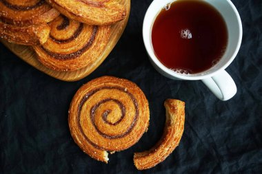 Tarçınlı ruloların yanında koyu arkaplanda bir fincan çay