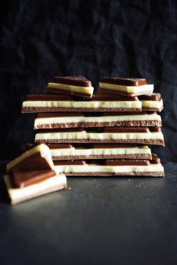 Süt parçaları, siyah arka planda siyah beyaz çikolata.