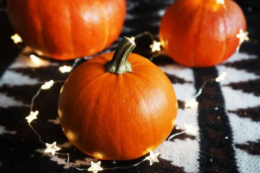 Battaniyeye ışık tutulmuş turuncu balkabakları ve etnik desenler.