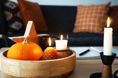 Modern bir iç mekanda yanan mumlar ve farklı sonbahar dekorları.