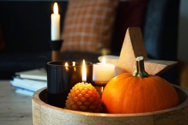 Modern bir iç mekanda yanan mumlar ve farklı sonbahar dekorları.