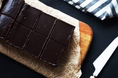 Tahtada çikolatalı kek, bıçağın yanında ve arka planda bir havlu.