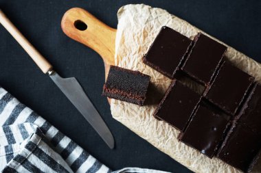 Tahtada çikolatalı kek, bıçağın yanında ve arka planda bir havlu.