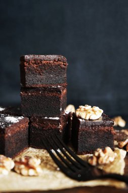 Cevizlerin yanında çikolatalı brownie ve siyah bir arka planda tahta bir çatal.