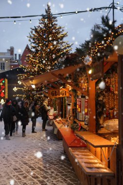 Noel ağacının ve düşen karın arka planında sıcak şarap ve her türlü yiyecekle dolu bir dükkan. 