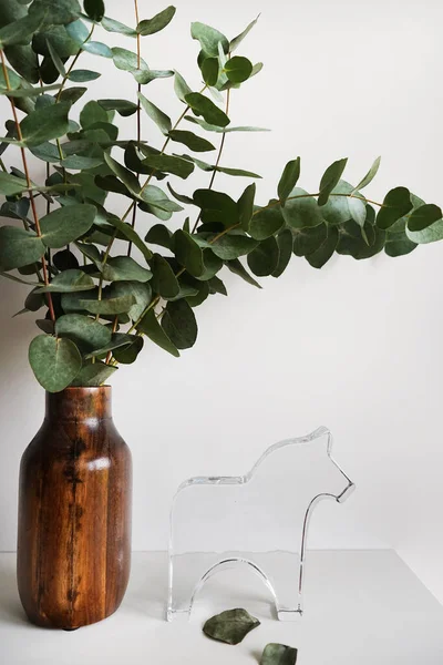 Eucalyptus branches in a wooden vase on a light background