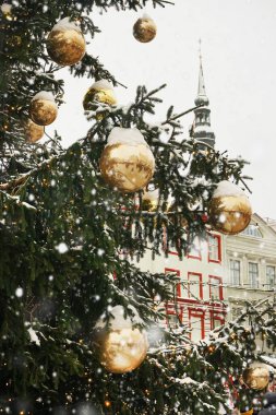 Noel ağacındaki altın Noel ağacı süslemeleri eski bir binanın arka planındaki ışıkların arasında