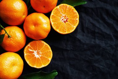 Siyah arkaplanda kesilmiş mandalinalar var.