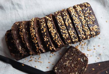 Keten peçetede siyah bir bıçağın yanında dilimlenmiş siyah ekmek.